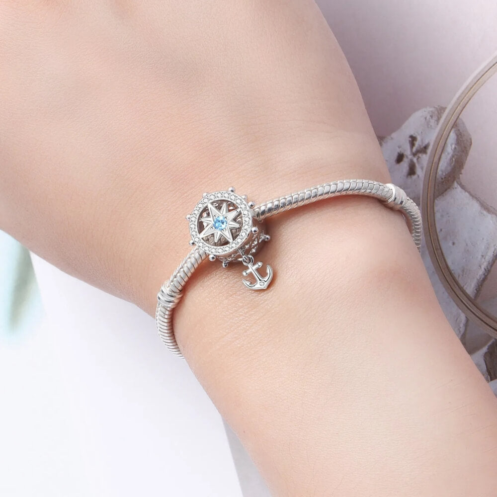 Sterling silver compass charm with anchor and blue crystal center.