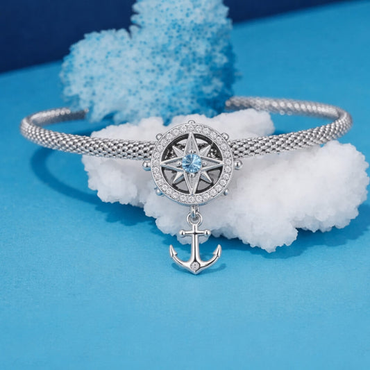 Sterling silver compass charm with anchor and blue crystal center.