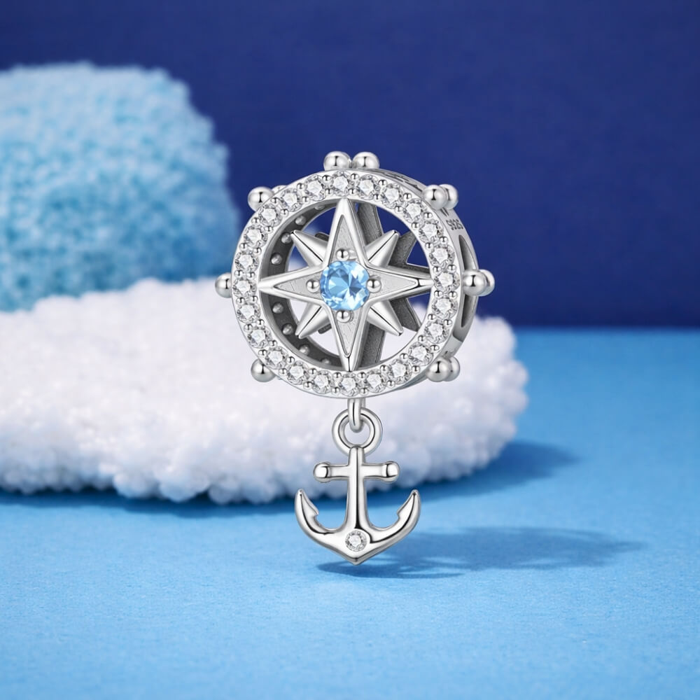 Sterling silver compass charm with anchor and blue crystal center.