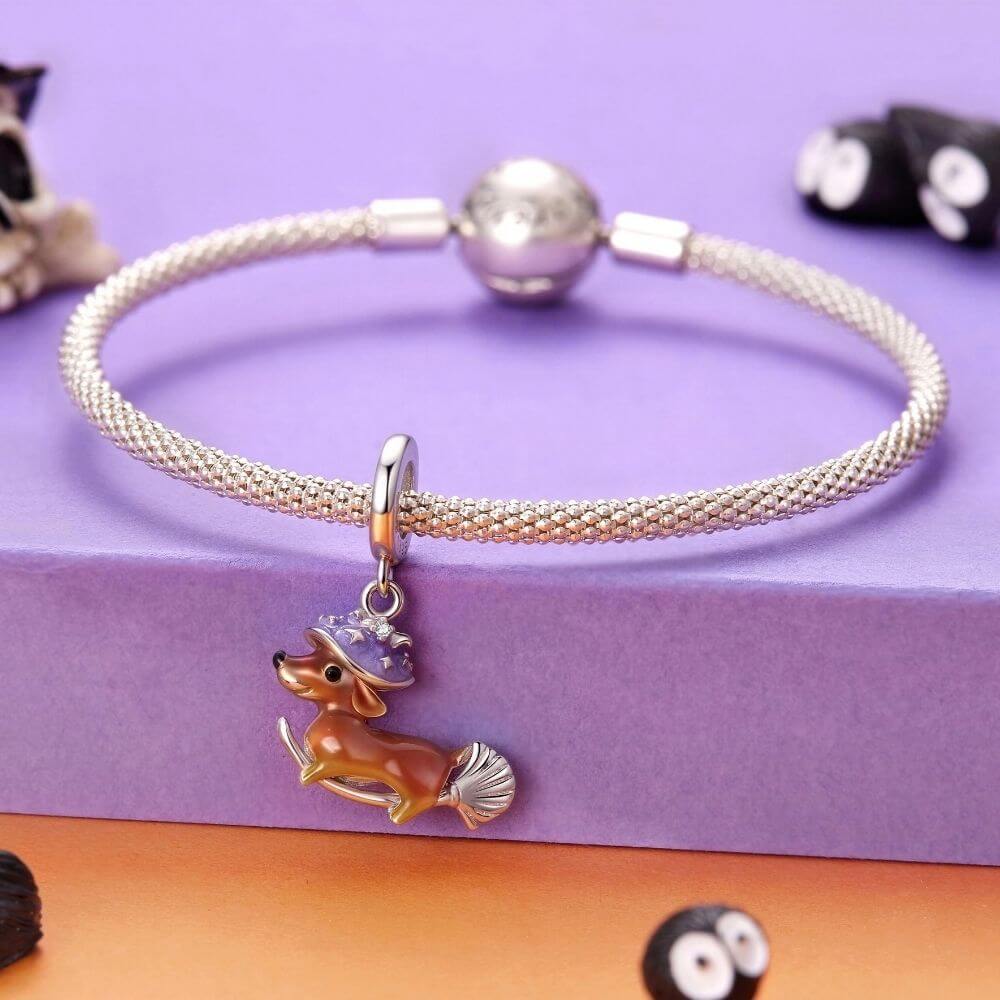 Sterling silver dachshund witch charm with purple hat, broomstick, and playful Halloween details.