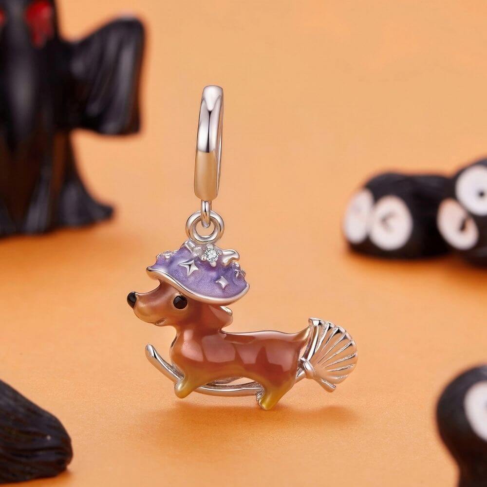 Sterling silver dachshund witch charm with purple hat, broomstick, and playful Halloween details.