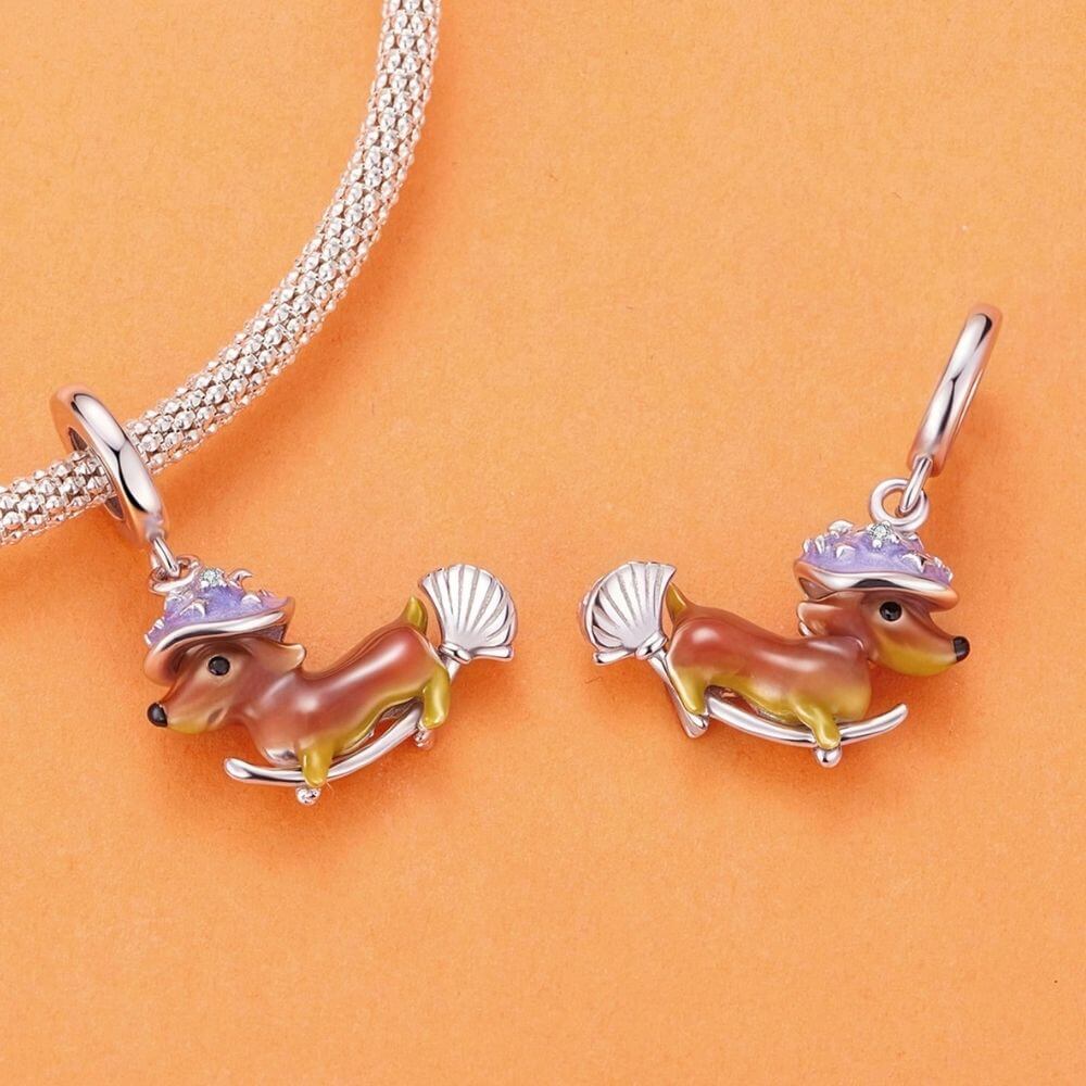 Sterling silver dachshund witch charm with purple hat, broomstick, and playful Halloween details.