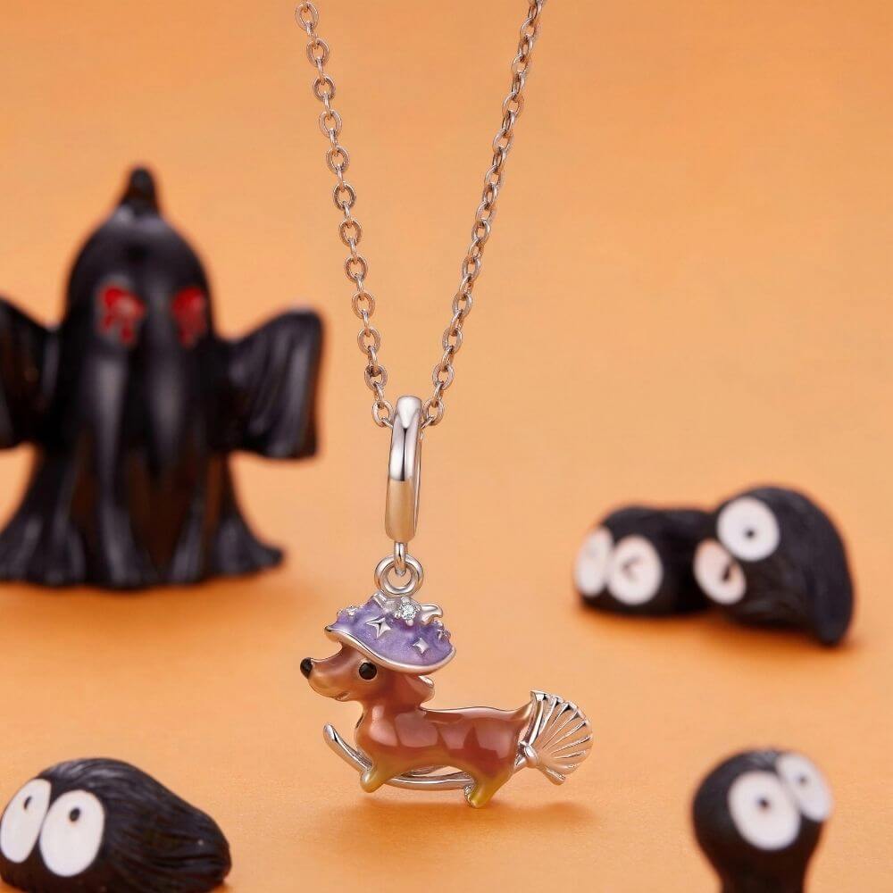 Sterling silver dachshund witch charm with purple hat, broomstick, and playful Halloween details.