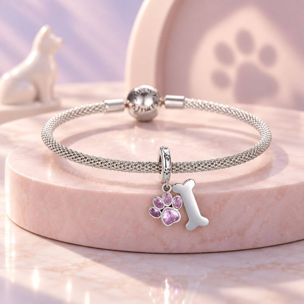 Sterling silver dog paw charm with pink crystal paw print, bone dangle, and playful pet-inspired details.