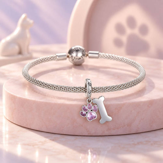 Sterling silver dog paw charm with pink crystal paw print, bone dangle, and playful pet-inspired details.