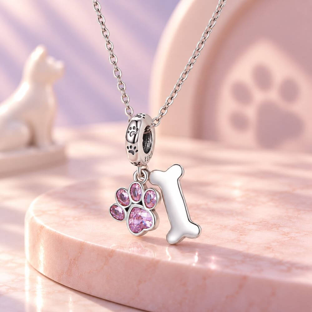 Sterling silver dog paw charm with pink crystal paw print, bone dangle, and playful pet-inspired details.