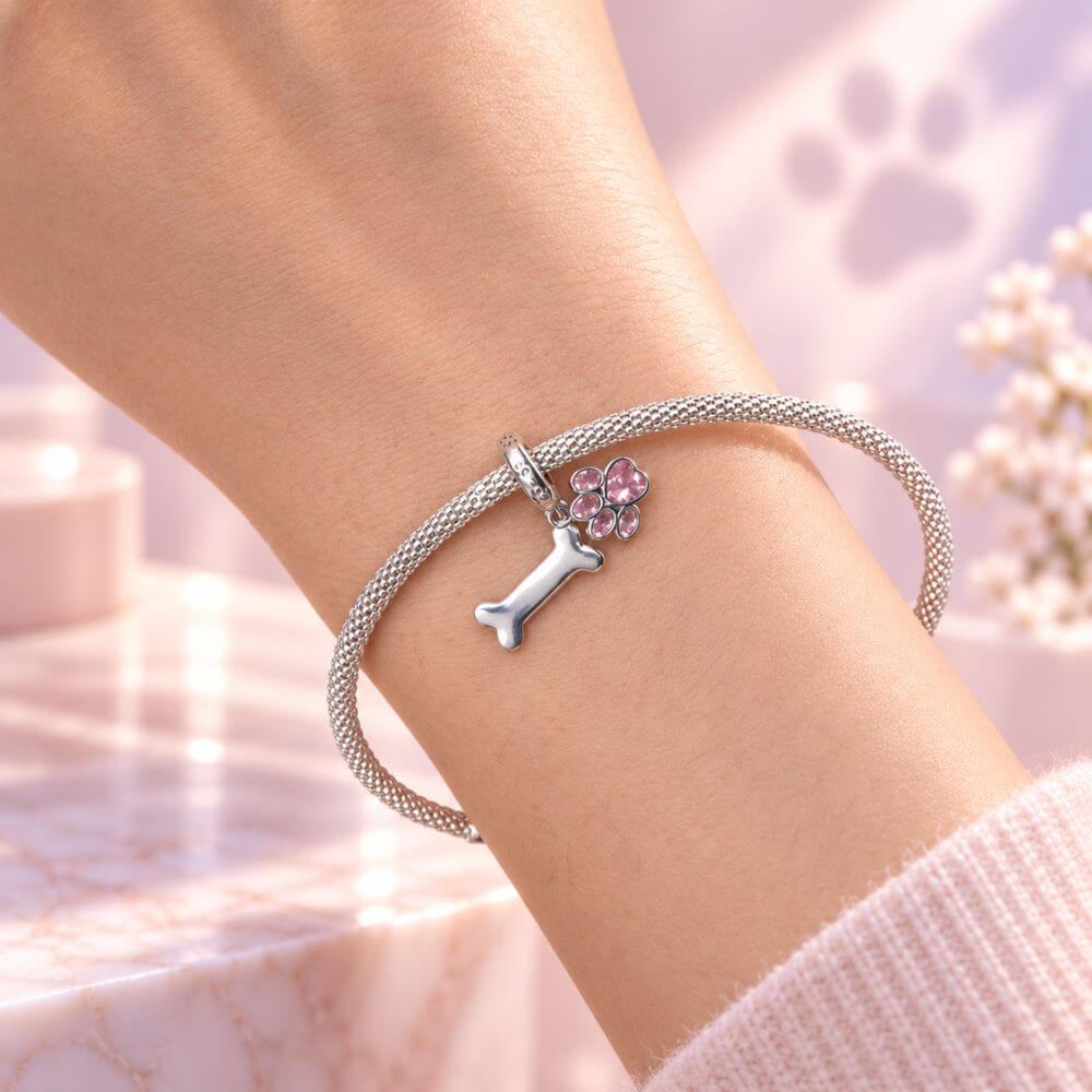 Sterling silver dog paw charm with pink crystal paw print, bone dangle, and playful pet-inspired details.