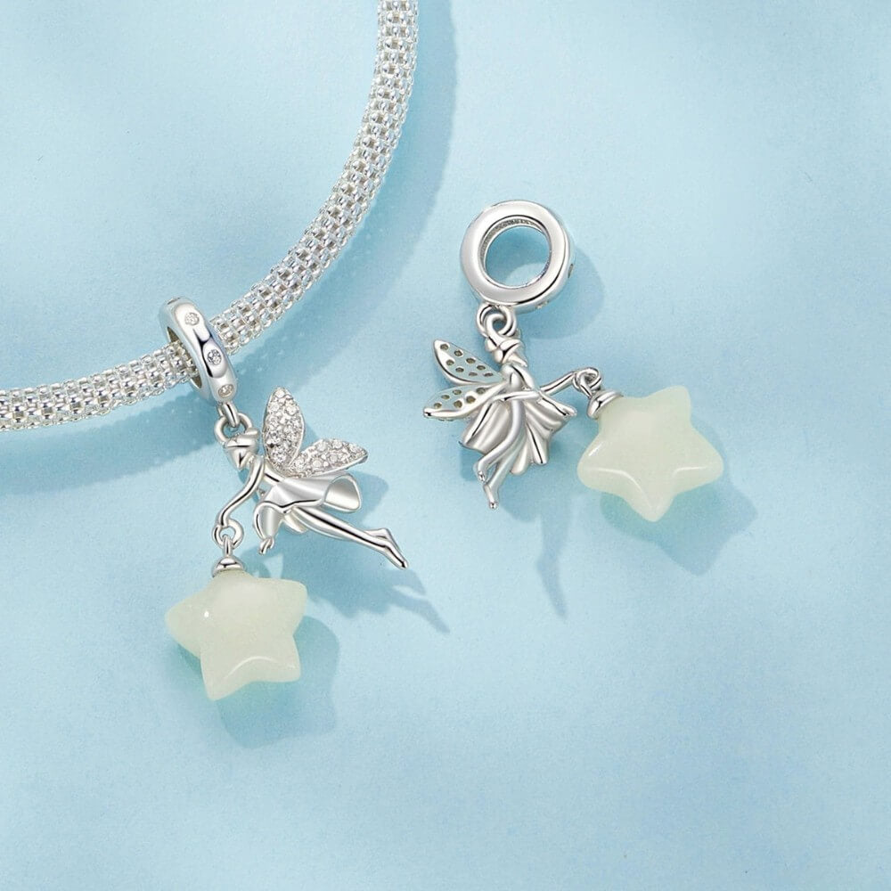 Sterling silver fairy charm holding glowing star with crystal wing details.