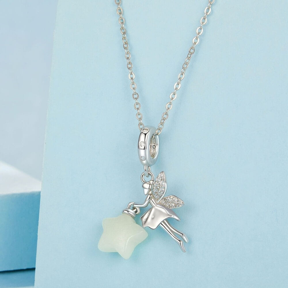 Sterling silver fairy charm holding glowing star with crystal wing details.