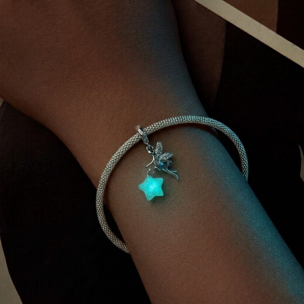 Sterling silver fairy charm holding glowing star with crystal wing details.