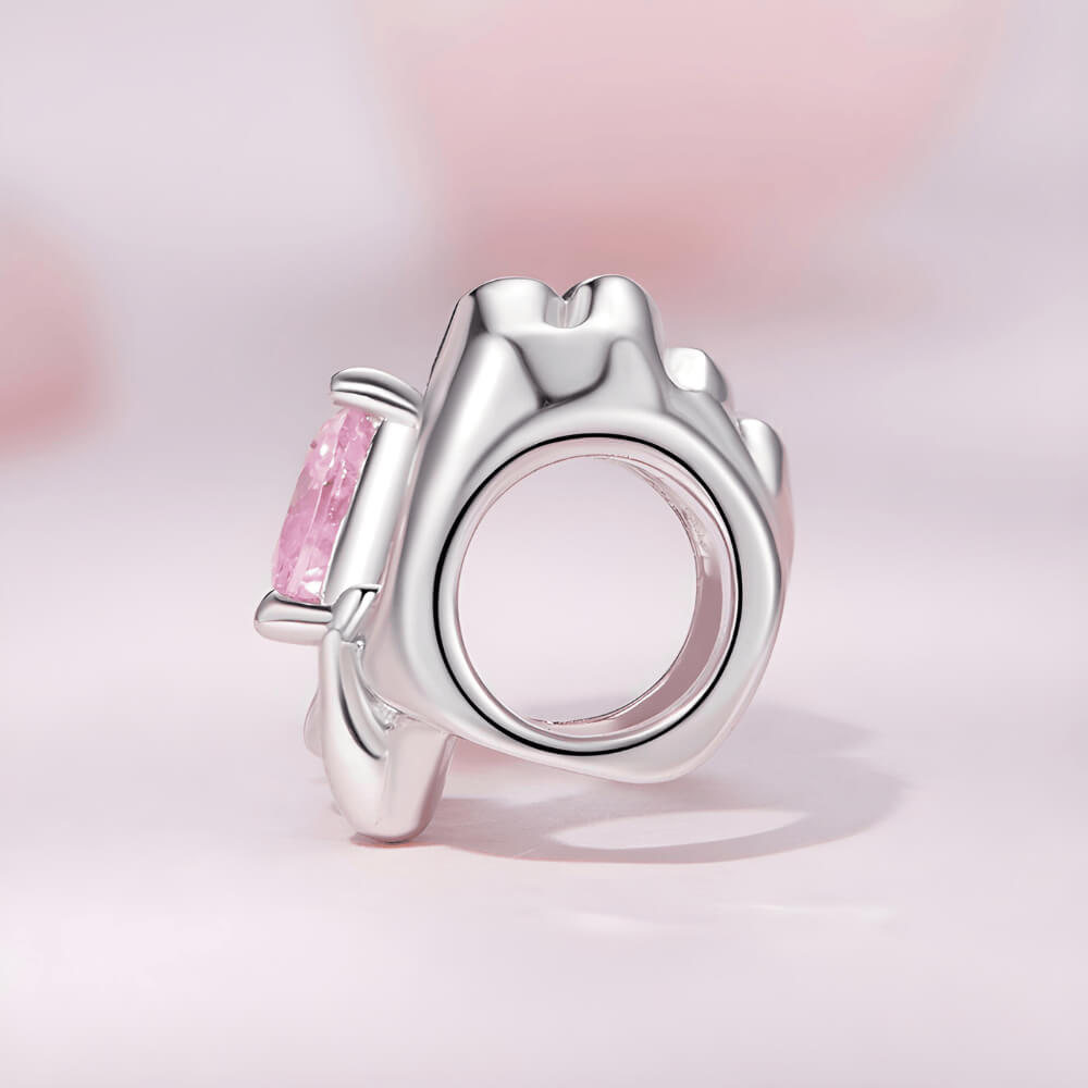 Sterling silver charm with adult and child hands forming a heart around a pink crystal 
