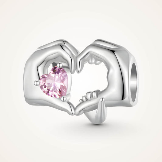 Sterling silver charm with adult and child hands forming a heart around a pink crystal – ORÉYA