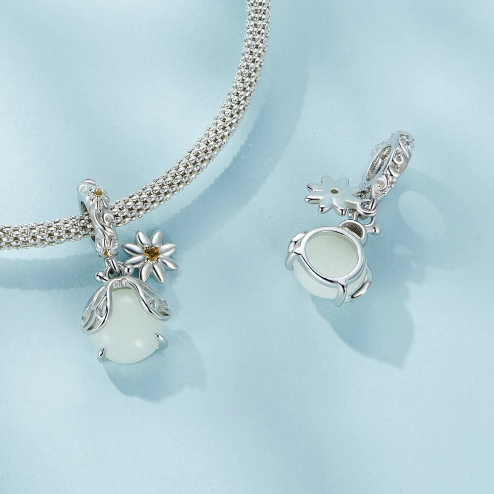 Sterling silver firefly charm with mint glowing enamel body and yellow flower detail.