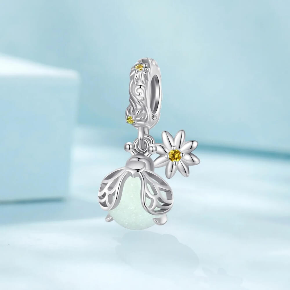 Sterling silver firefly charm with mint glowing enamel body and yellow flower detail.
