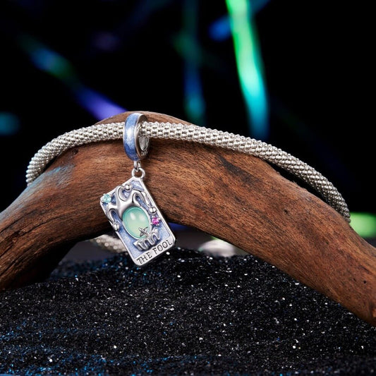 Sterling silver tarot charm with green crystal and blue enamel details.