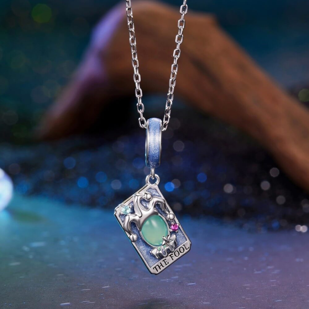 Sterling silver tarot charm with green crystal and blue enamel details.
