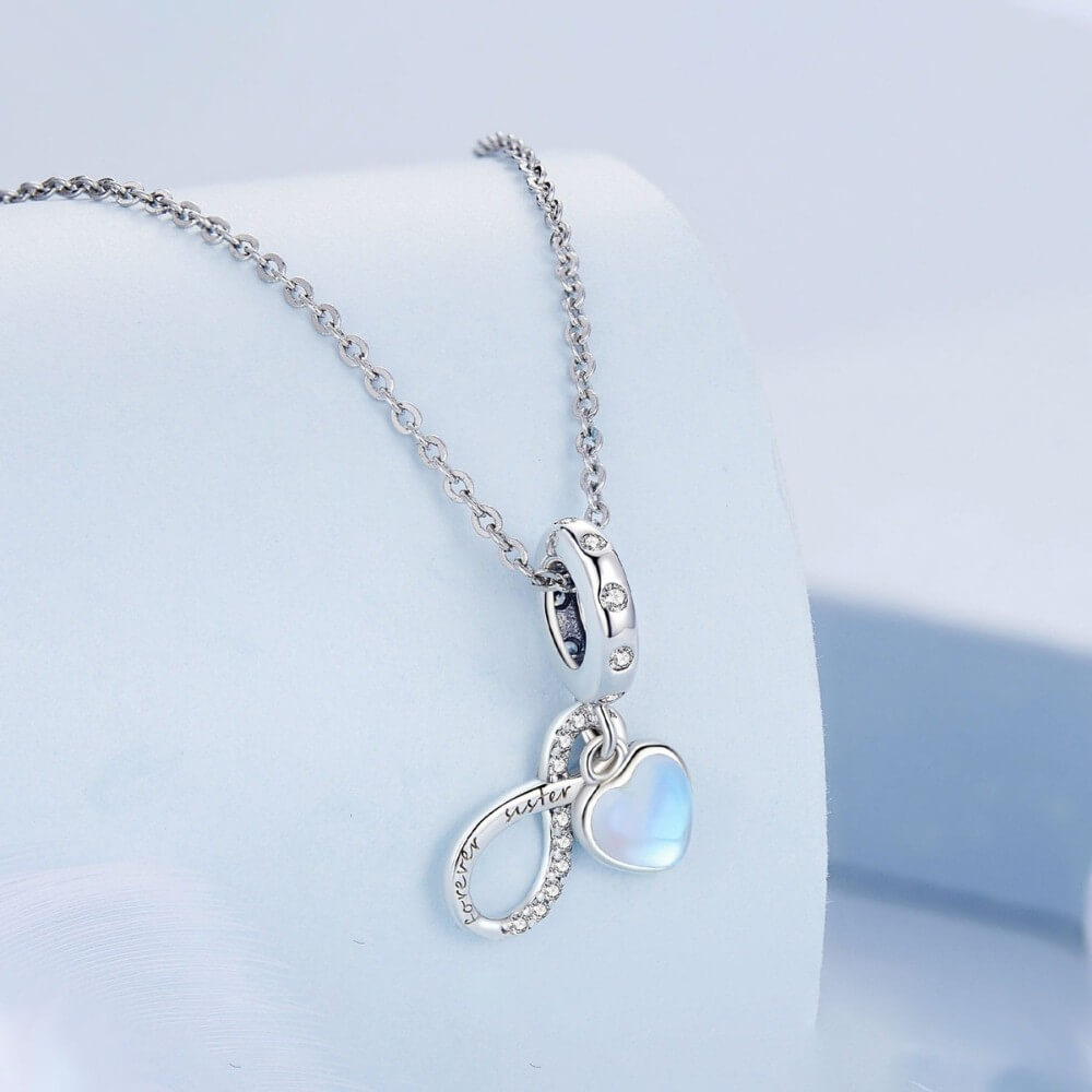 Sterling silver forever sister charm with blue heart and crystal infinity detail.