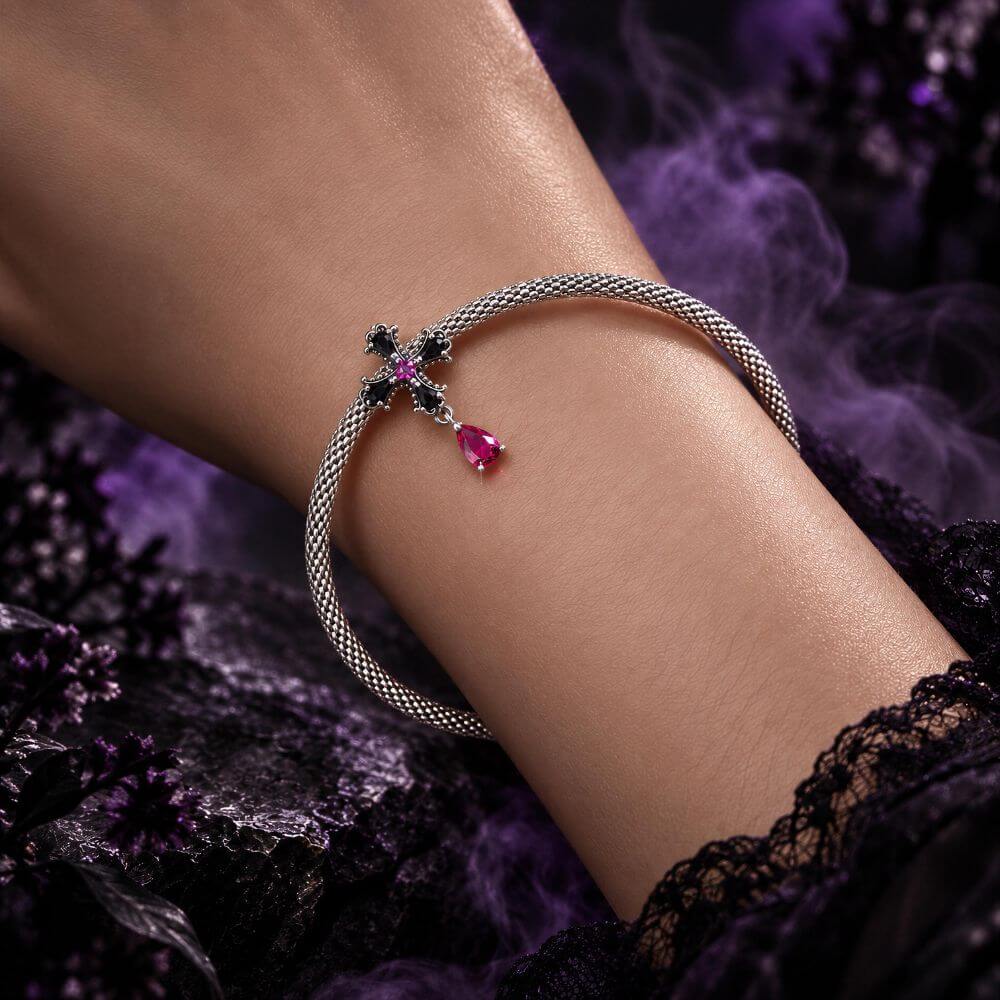 Sterling silver gothic cross charm with black crystals, pink center stone, and dangling magenta crystal drop.