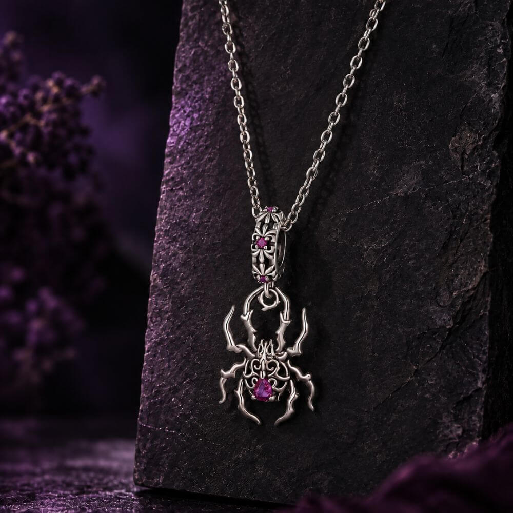 Sterling silver spider charm with gothic web details, pink crystals, and an ornate dangling body design.
