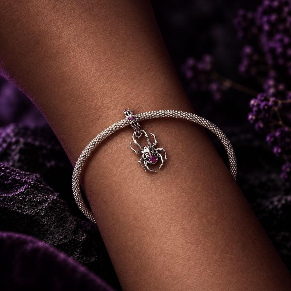 Sterling silver spider charm with gothic web details, pink crystals, and an ornate dangling body design.
