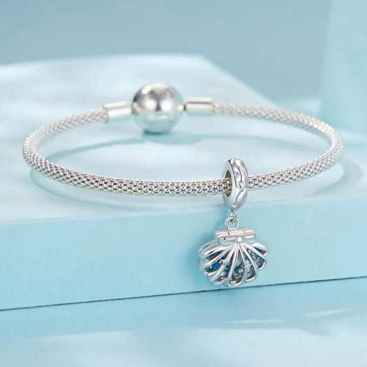 Sterling silver shell charm with hidden pearl and ocean blue enamel.