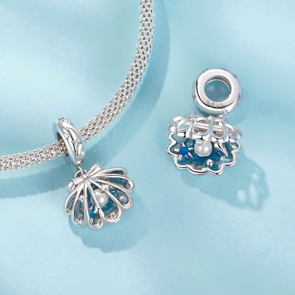 Sterling silver shell charm with hidden pearl and ocean blue enamel.