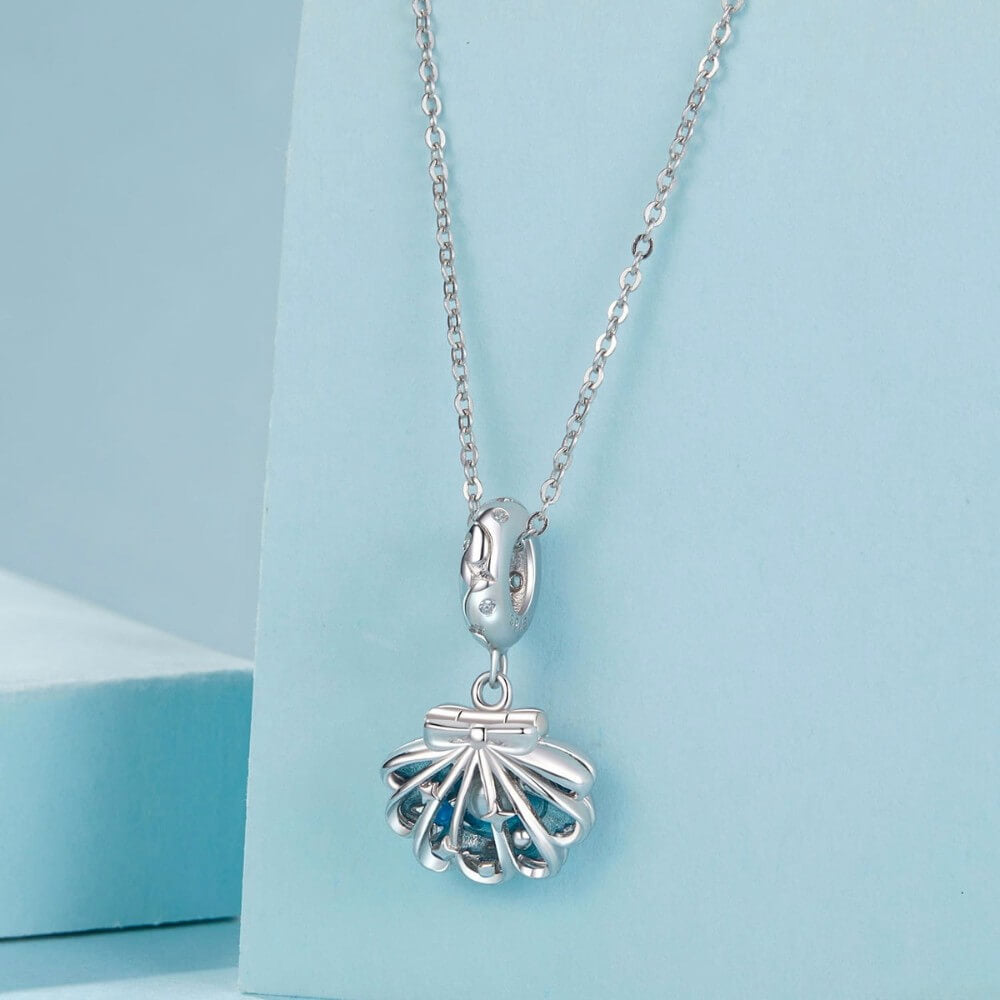 Sterling silver shell charm with hidden pearl and ocean blue enamel.