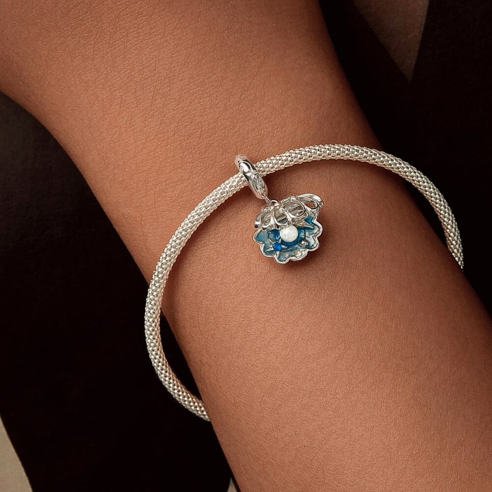 Sterling silver shell charm with hidden pearl and ocean blue enamel.