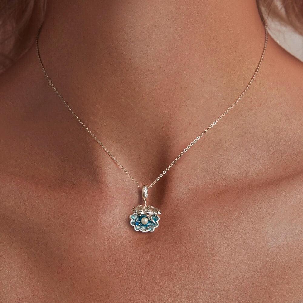 Sterling silver shell charm with hidden pearl and ocean blue enamel.