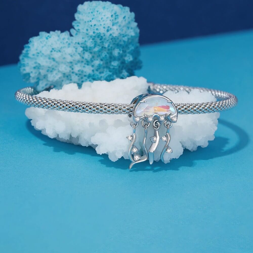 Silver bracelet with a jellyfish charm on a blue and white coral background