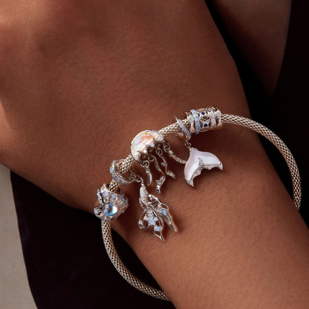 Sterling silver jellyfish charm with iridescent crystal and flowing tentacle details.