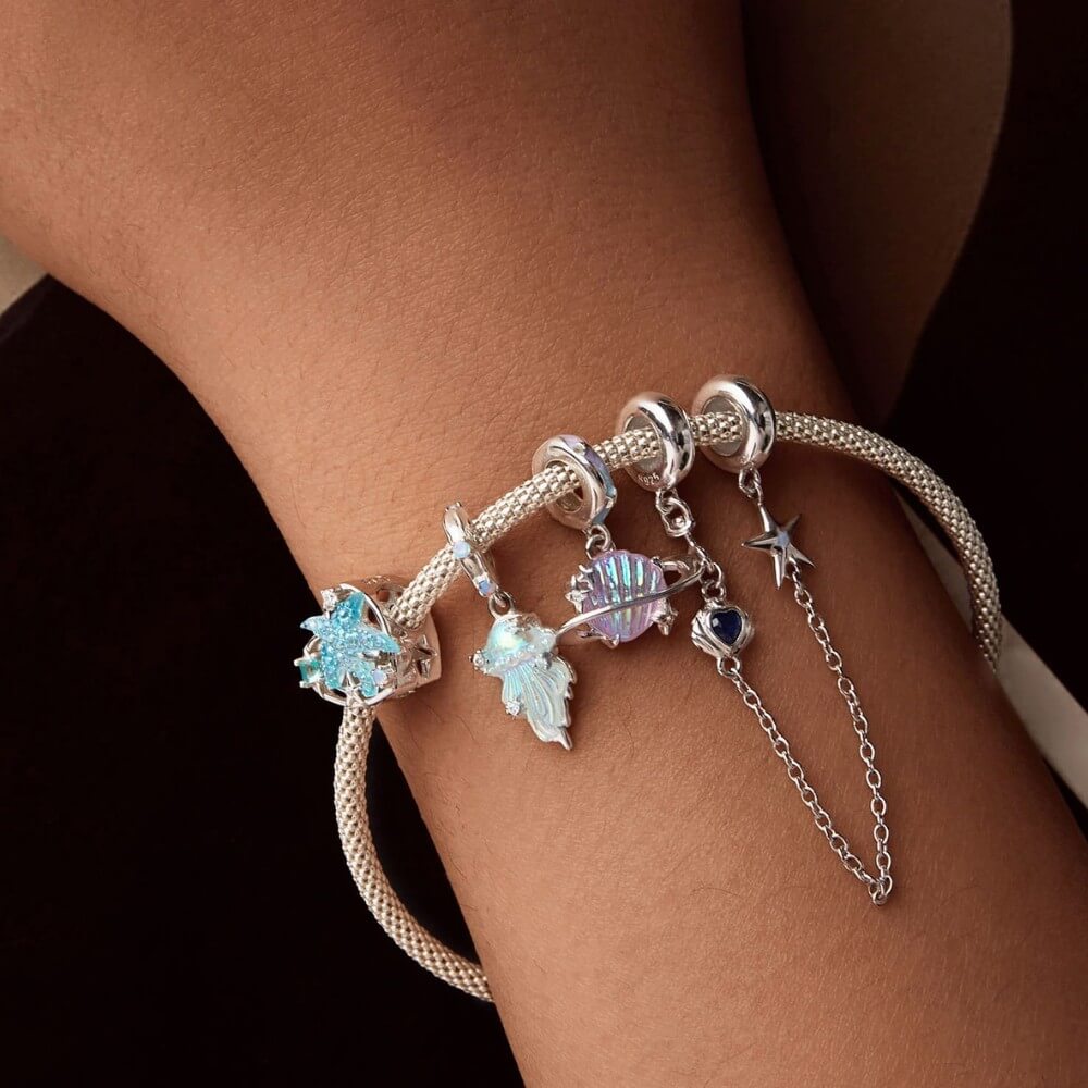 Sterling silver planet charm with iridescent shell design and star accents.