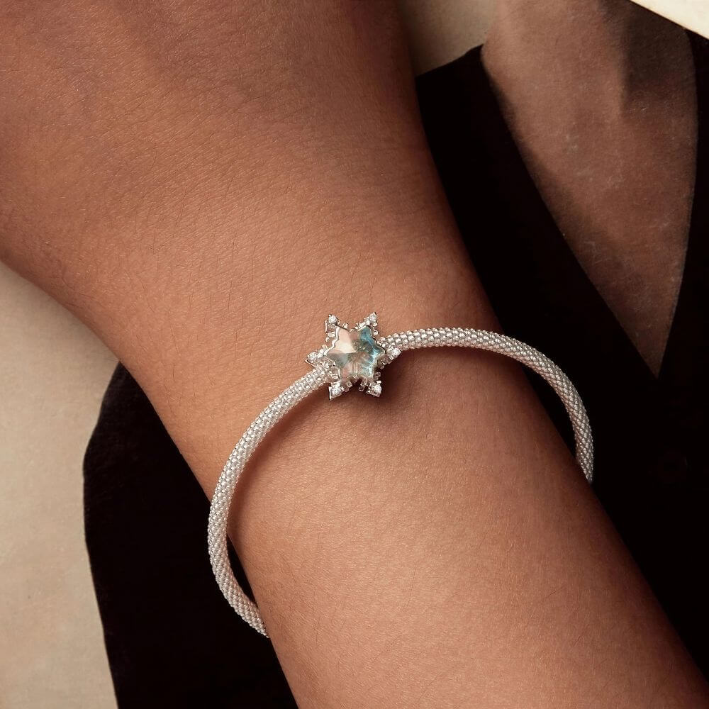 Sterling silver snowflake charm with iridescent crystal center and sparkling clear crystal accents.