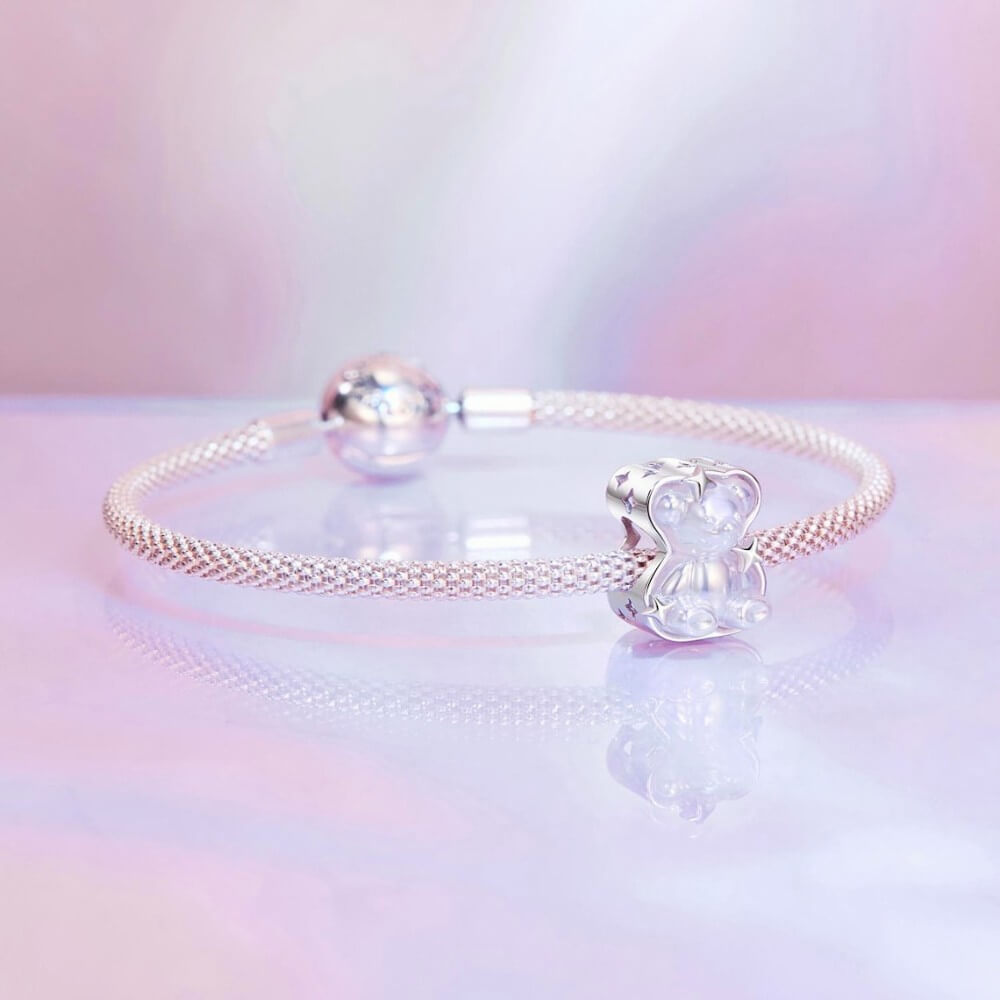Sterling silver teddy bear charm with iridescent finish and star details.