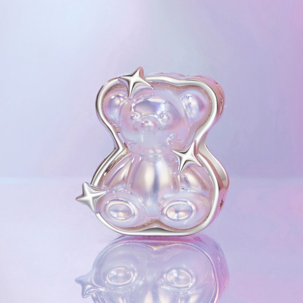 Sterling silver teddy bear charm with iridescent finish and star details.