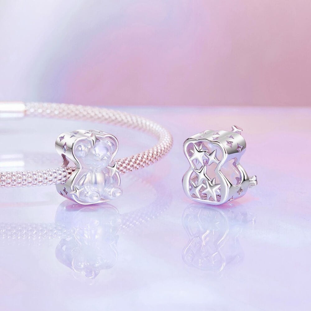Sterling silver teddy bear charm with iridescent finish and star details.