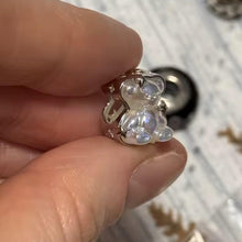 Sterling silver teddy bear charm with iridescent finish and star details.