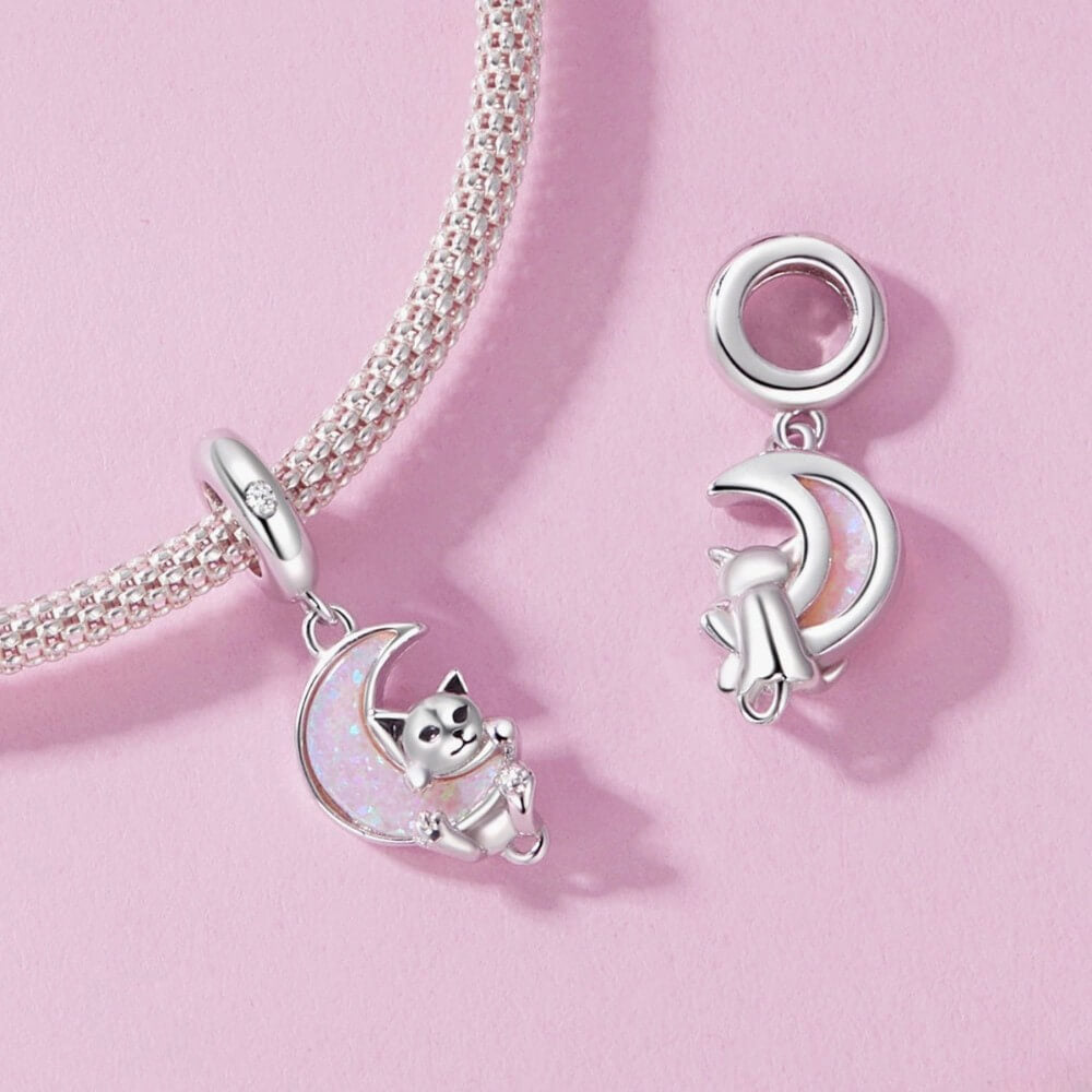 Sterling silver kitten charm with pink opal moon and star detail.