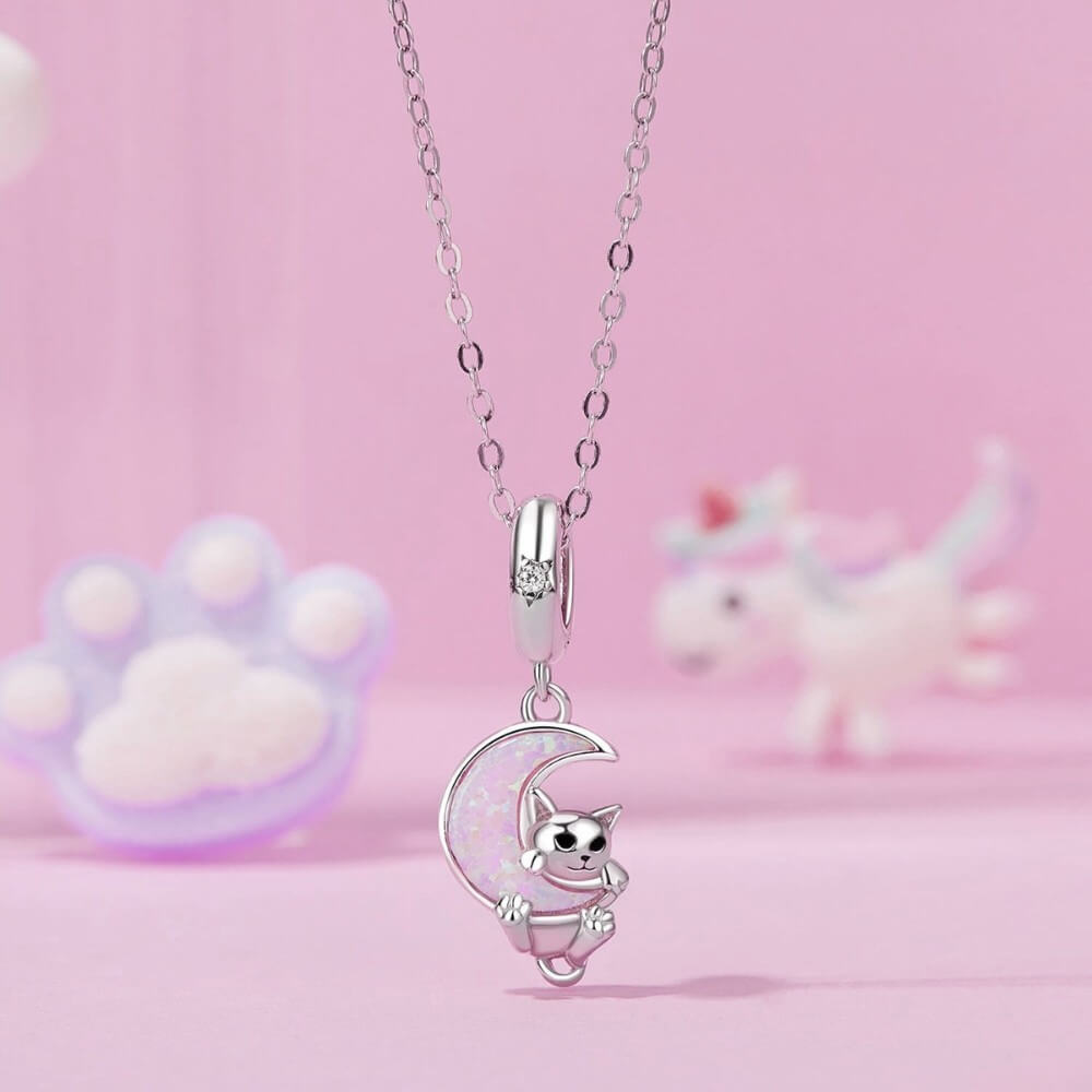 Sterling silver kitten charm with pink opal moon and star detail.