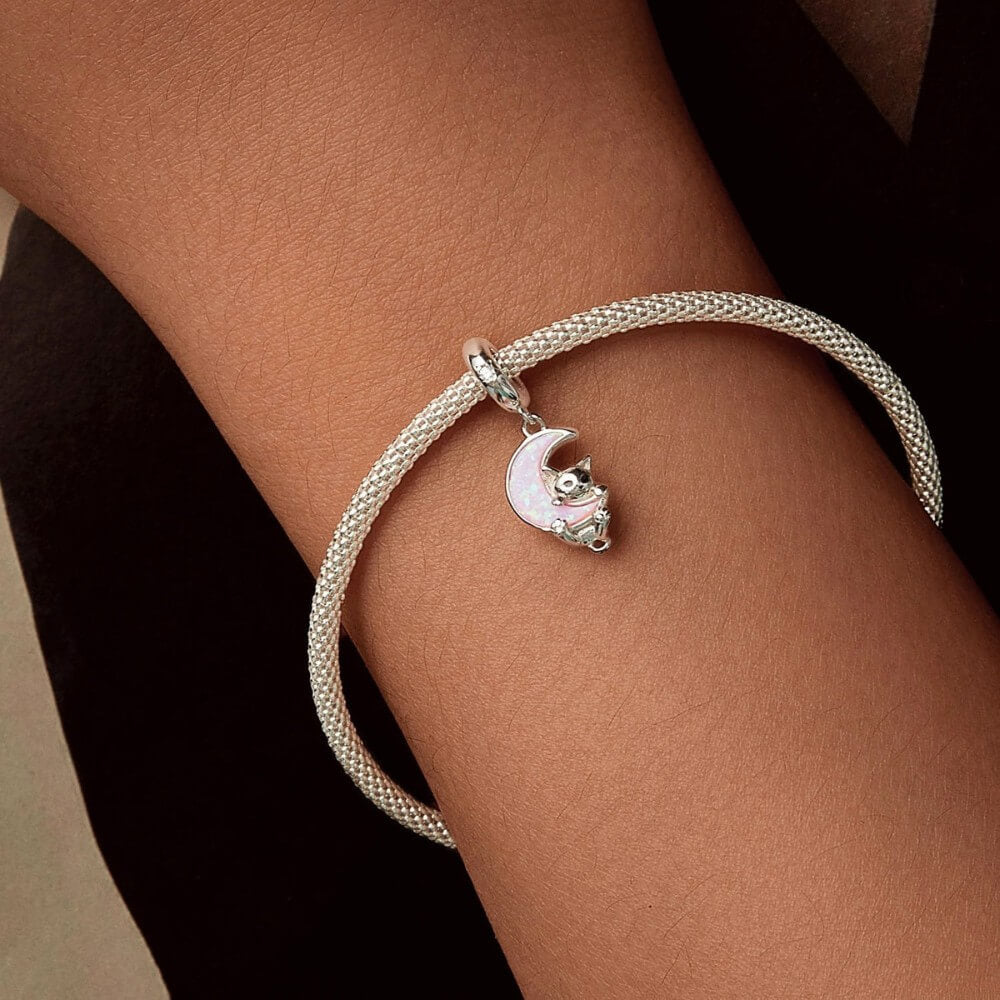 Sterling silver kitten charm with pink opal moon and star detail.