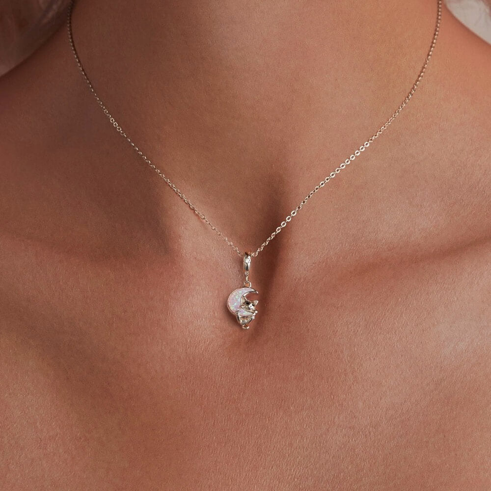 Sterling silver kitten charm with pink opal moon and star detail.