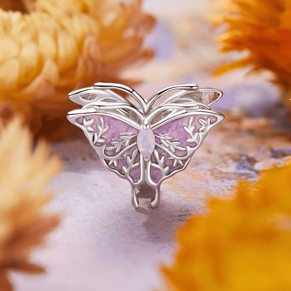 Sterling silver butterfly charm with lavender enamel wings, leaf-shaped filigree details, and an opal-like central gemstone