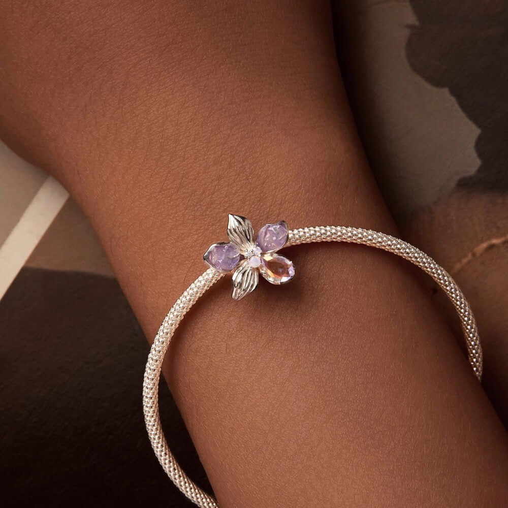 Sterling silver flower charm with lavender petals and iridescent crystal details.