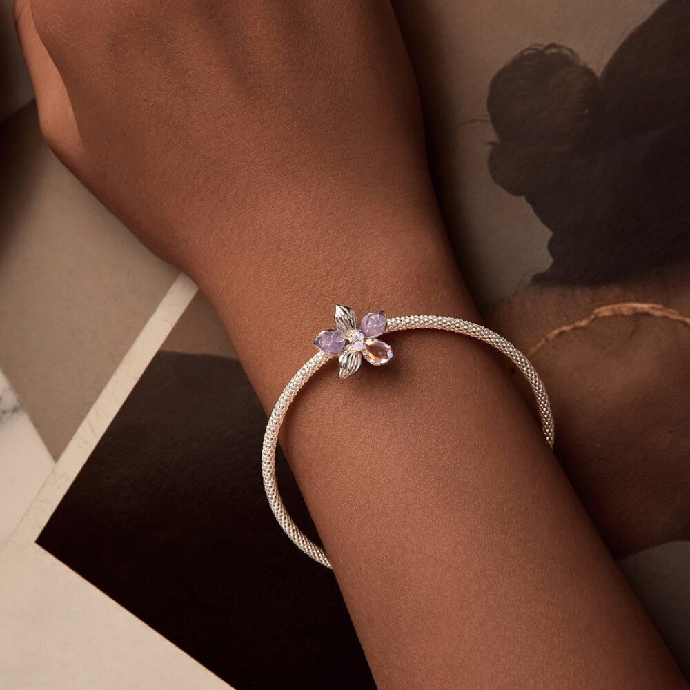 Sterling silver flower charm with lavender petals and iridescent crystal details.