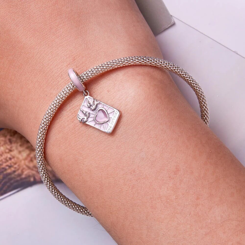 Sterling silver lovers promise charm with pink heart, doves, and engraved message.