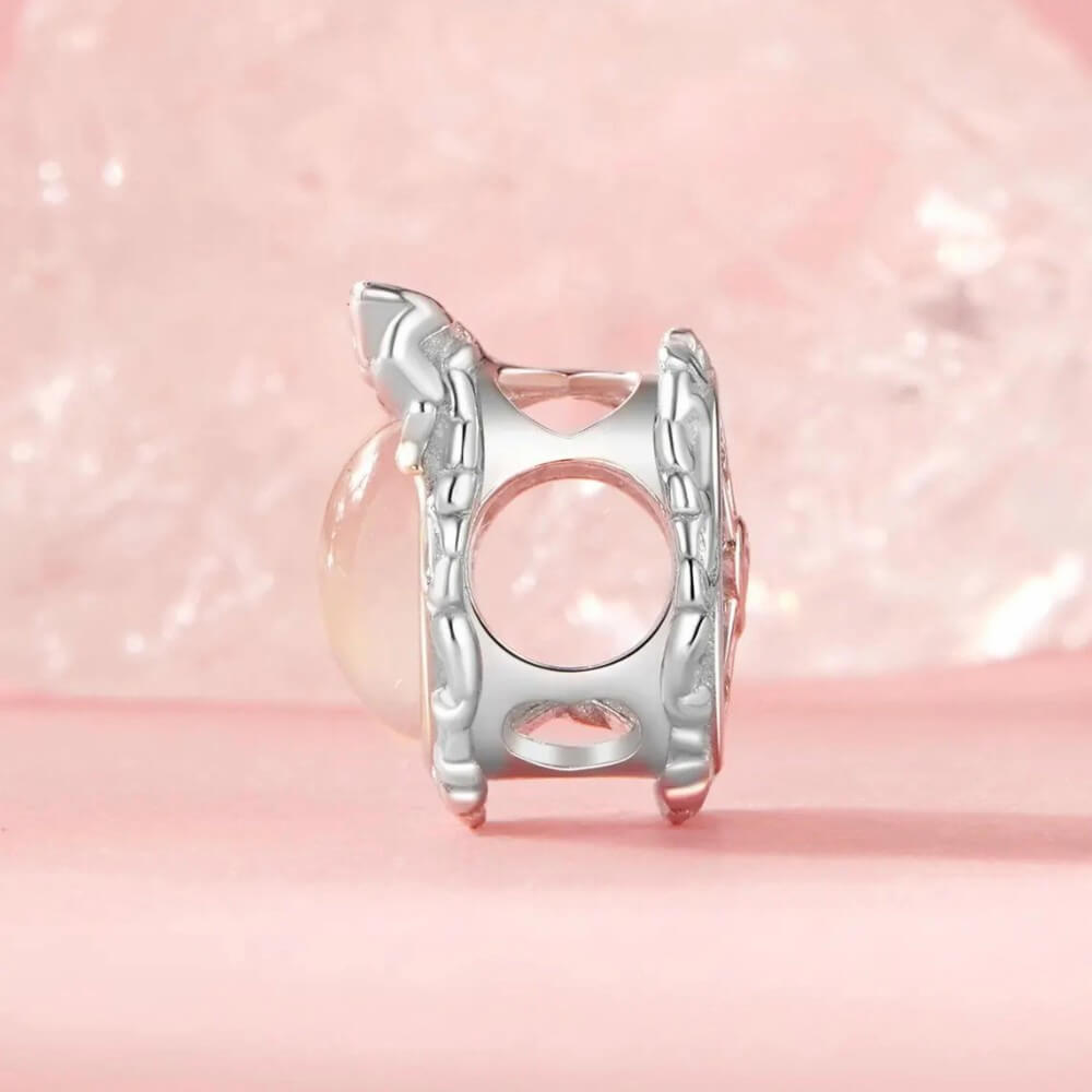 Sterling silver mirror charm with iridescent center and ornate bow frame.