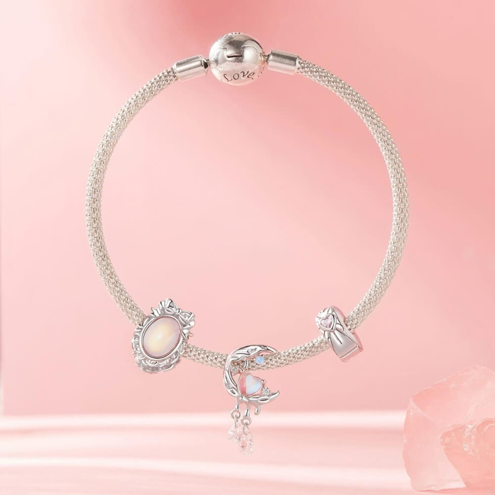 Sterling silver mirror charm with iridescent center and ornate bow frame.