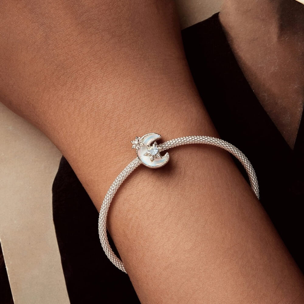 Sterling silver moon charm with iridescent enamel and floral crystal details.