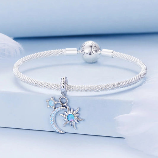 Silver bracelet with moon and sun charms on a light blue background