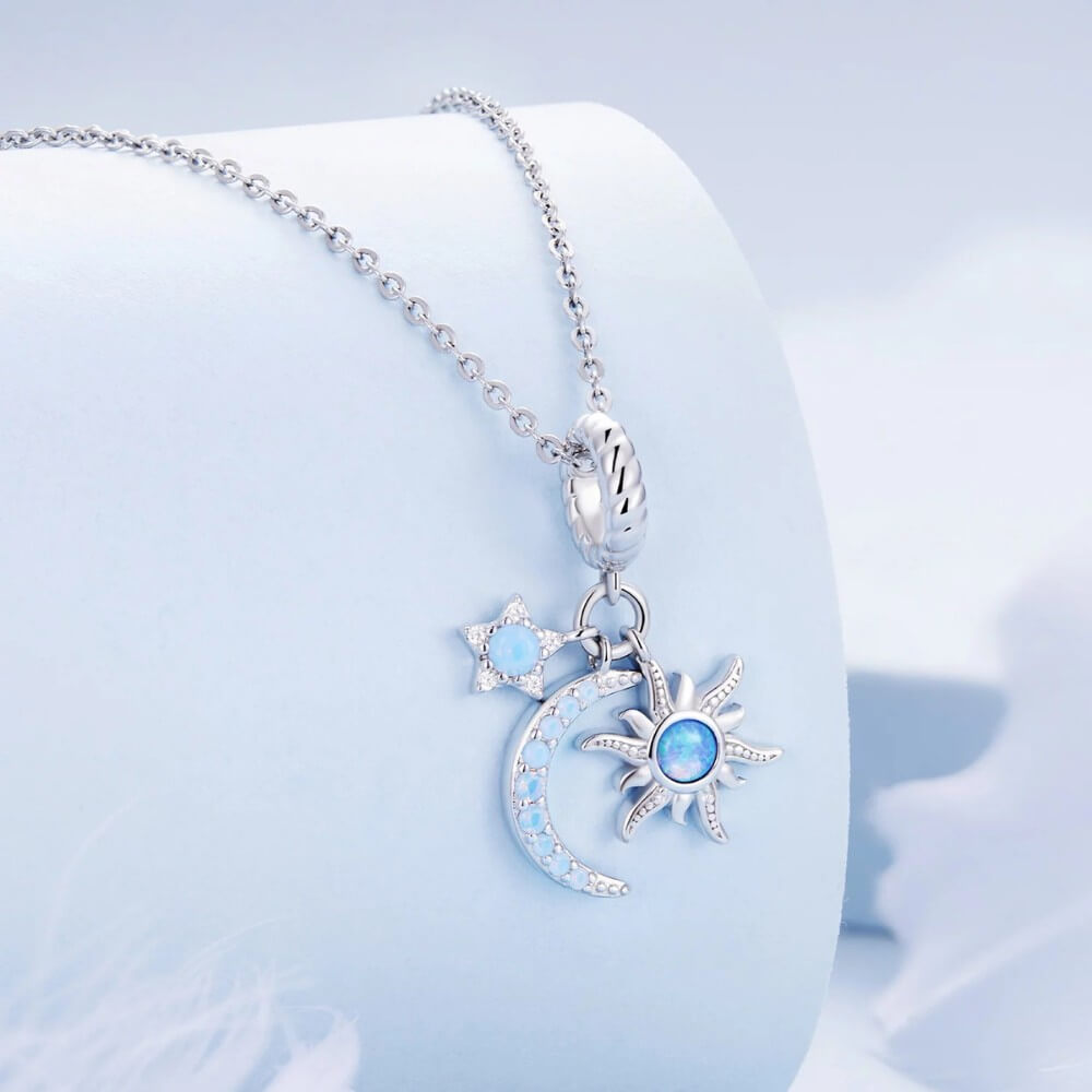 Sterling silver moon charm with sun, star, and blue opal details.